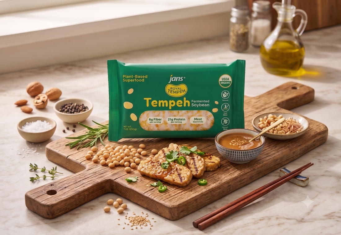 A professional wholesale product display showcasing a green package of Jans Royal Tempeh on a rustic wooden cutting board alongside grilled tempeh slices, a dish of dipping sauce, a small bowl of soybeans, and chopsticks.