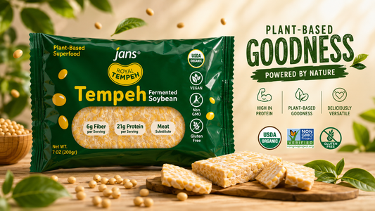 A green package of Jans Royal Tempeh Fermented Soybean displayed next to slices of raw tempeh and loose soybeans on a wooden board with text reading Plant-Based Goodness Powered by Nature.