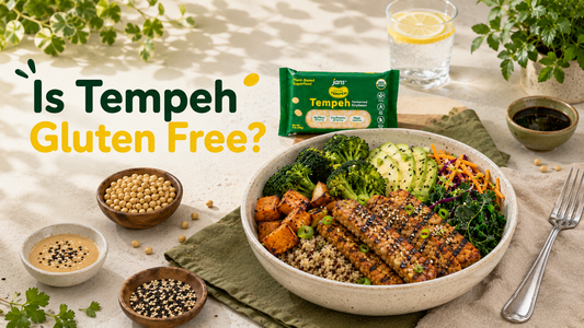 A nourishing grain bowl topped with grilled, seasoned tempeh strips, broccoli, and vegetables, displayed on a wooden table next to a green package of Jans Tempeh and a graphic overlay that reads "Is Tempeh Gluten Free?".