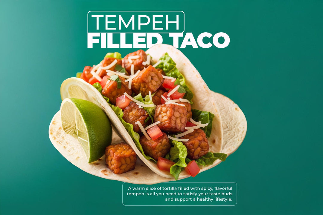 Tempeh-filled taco with diced tomatoes, shredded lettuce, grated cheese, and lime wedge on the side, showcasing a plant-based, flavorful tortilla meal.