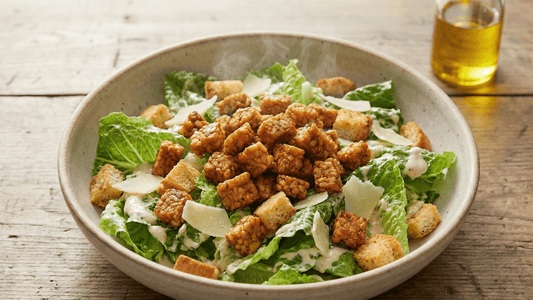 A vibrant bowl of tempeh caesar salad recipe featuring crisp romaine lettuce, crunchy croutons, and golden-brown Royal Tempeh cubes drizzled with a creamy vegan dressing.