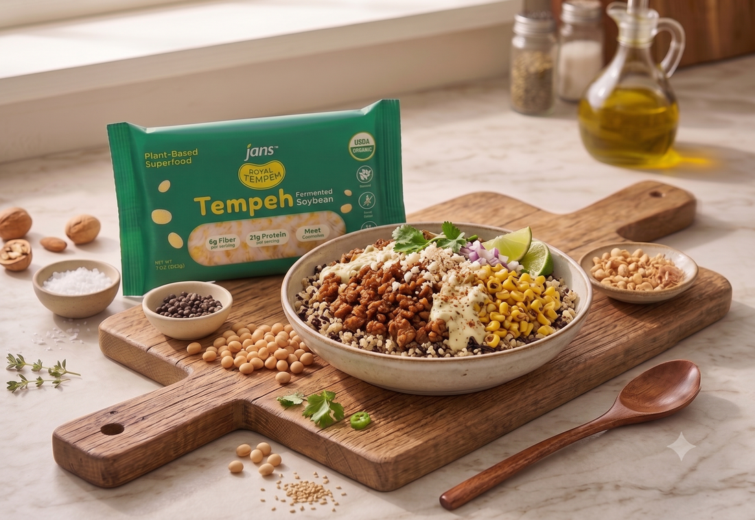 A wholesome plant-based grain bowl topped with crumbled seasoned tempeh, charred sweet corn kernels, chopped red onions, and lime wedges, displayed on a wooden board next to a green package of Royal Tempeh.