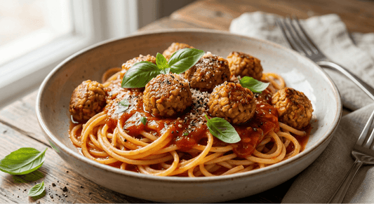 A bowl of spaghetti topped with golden-brown tempeh meatballs recipe, rich marinara sauce, and fresh basil leaves.