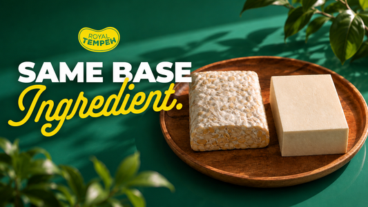 A wooden tray showcasing a textured slab of fermented tempeh and a smooth block of tofu side by side, framed by lush leaves and text reading SAME BASE INGREDIENT with the Royal Tempeh logo.