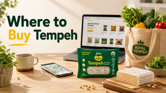 A wooden desk displaying a laptop showing an online store interface, a smartphone, green packages of Jans Tempeh, and a raw soybean block next to a canvas tote bag, with a graphic text overlay reading "Where to Buy Tempeh".
