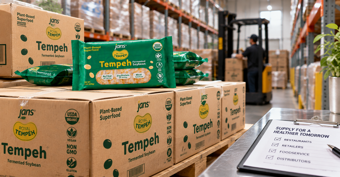 Stacks of Royal Tempeh wholesale cardboard cases and packaged tempeh in a distribution warehouse with a clipboard checklist and forklift in the background.