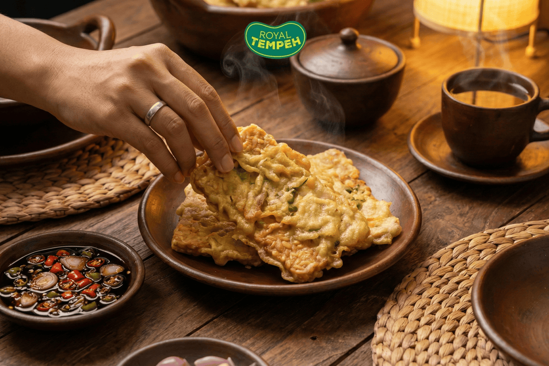 Hand grabbing crispy fried tempeh with chili dipping sauce.