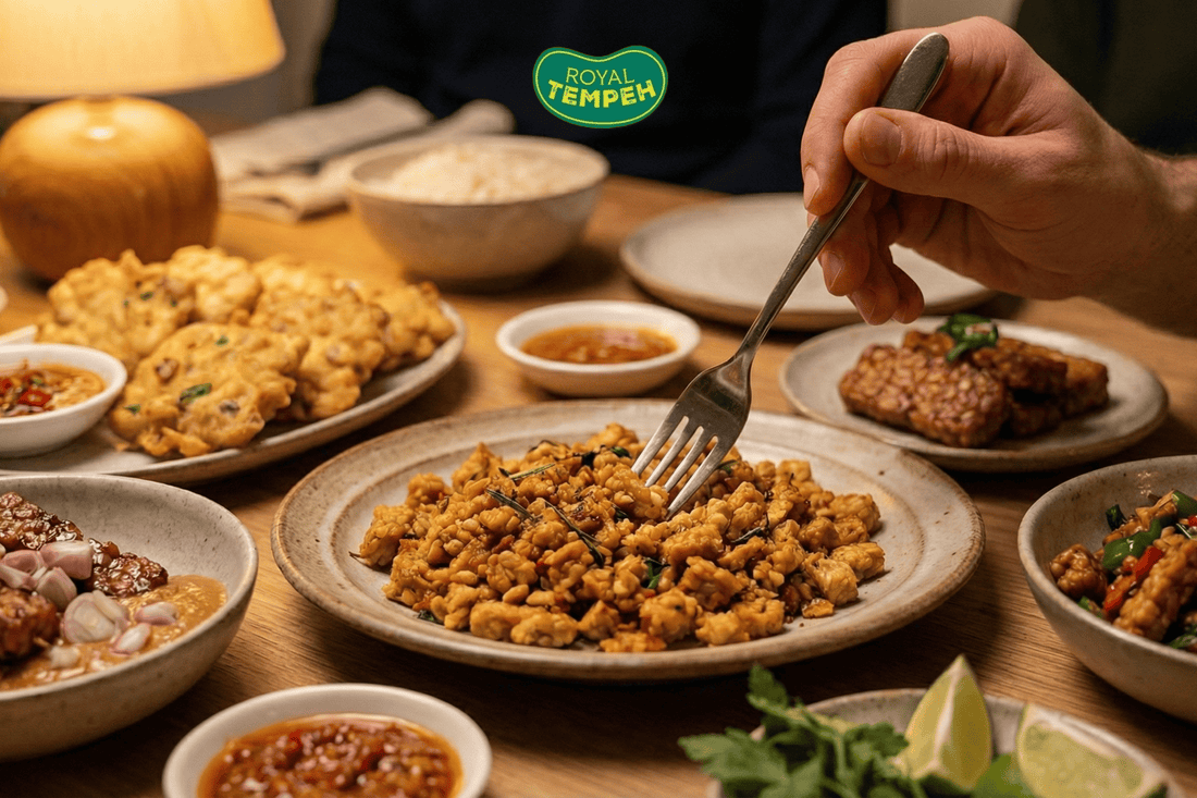 Hand serving tempeh dishes on a shared dinner table.