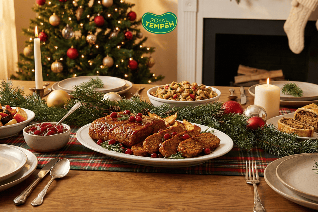 Festive holiday table with glazed tempeh roast, candles, and Christmas tree backdrop.