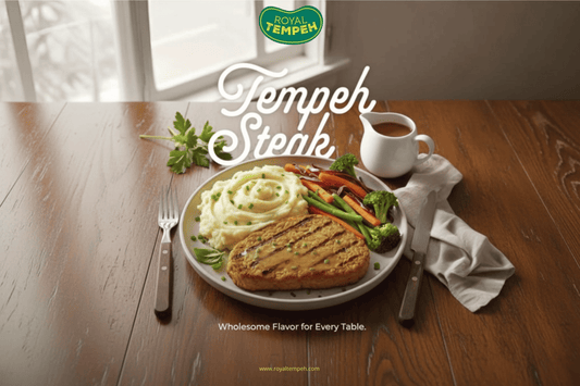 Royal Tempeh steak with mashed potatoes and vegetables served on a wooden table.