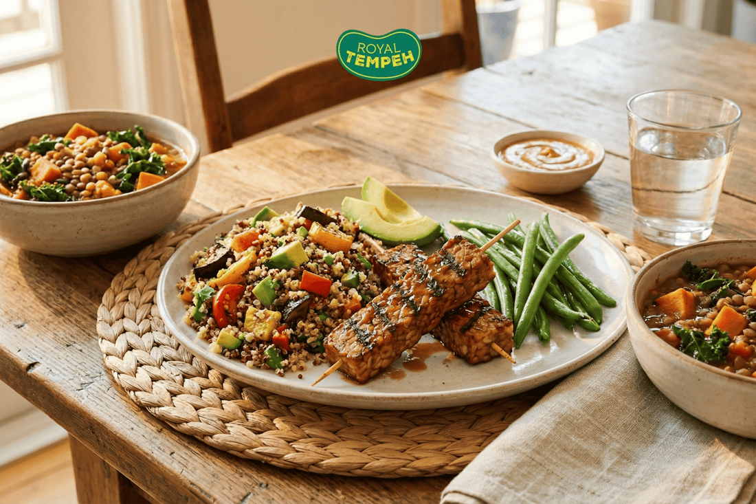 Balanced meal with glazed tempeh skewers, quinoa salad, green beans, and avocado on wooden table.