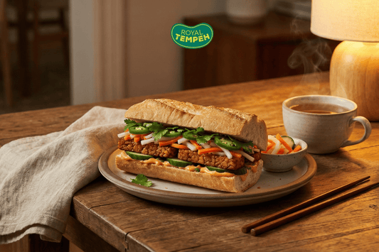 Royal Tempeh bánh mì sandwich with pickled vegetables, cilantro, and jalapeños served on a rustic table with hot tea.
