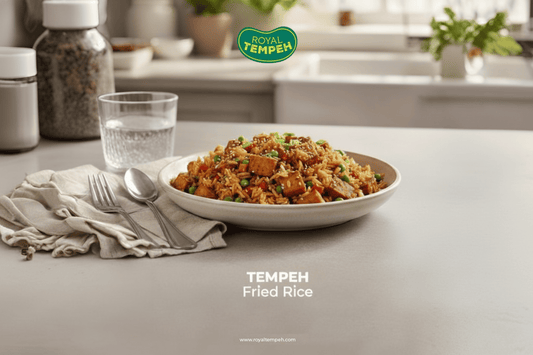 Royal Tempeh Fried Rice served in a bowl on a clean kitchen counter, garnished with vegetables and sesame seeds.