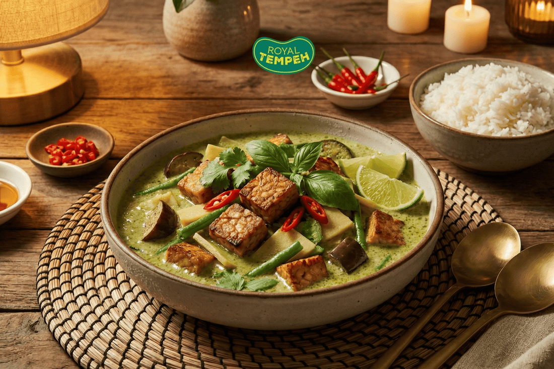 Royal Tempeh green curry with vegetables, lime, and herbs served in a rustic bowl with rice and chilies on the side.