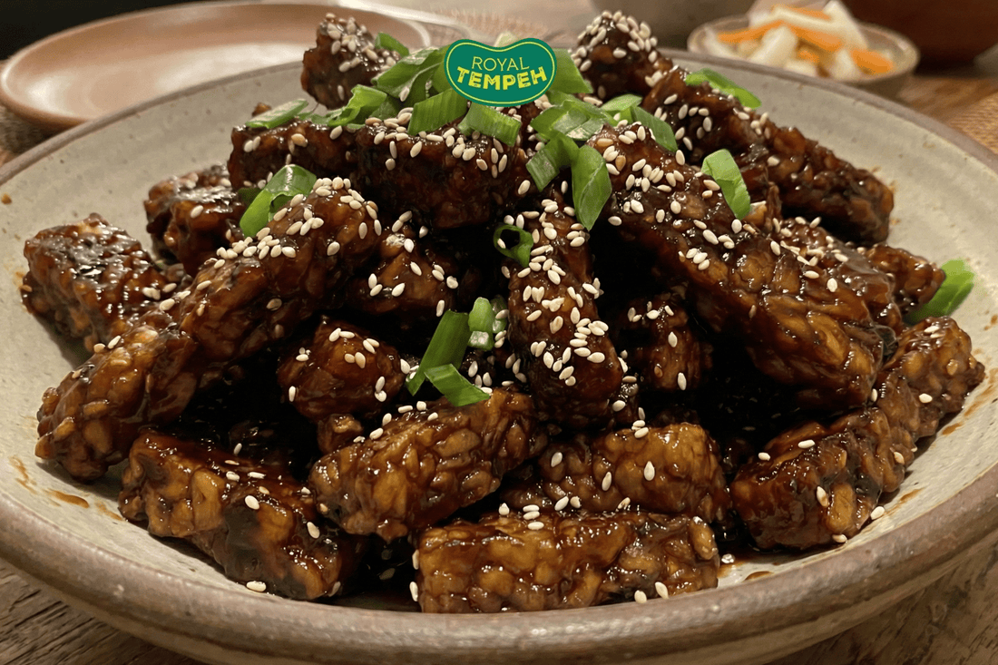 Glazed tempeh cubes coated in a rich savory sauce, topped with sesame seeds and chopped scallions, served as a protein-packed plant-based tempeh dish and flavorful meat substitute.