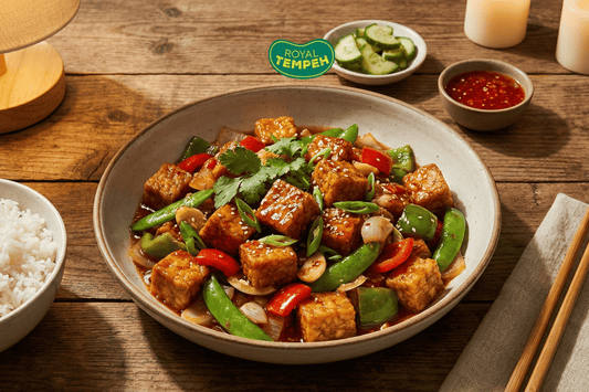 Royal Tempeh stir-fry with peppers, snap peas, and onions served in a rustic bowl with rice, pickles, and chili sauce on the side.